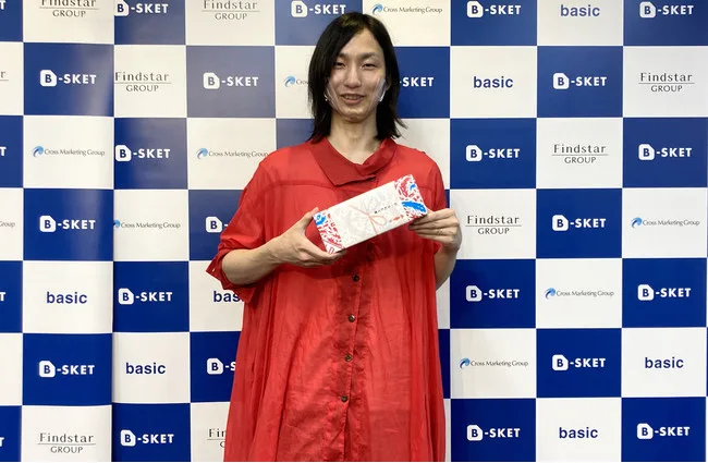 B-SKET のバックパネルの前で受賞の賞状を持つ LeanGo 代表の平井